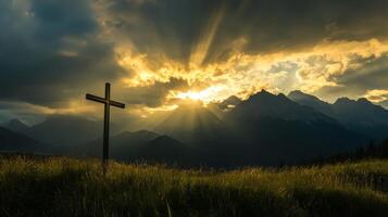 Sunset over mountain peaks with cross in foreground photo