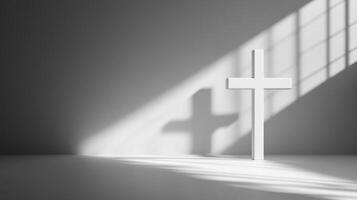 Shadow of cross on white background with sunlight beam cast in grayscale photo
