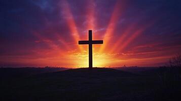 Dramatic sunset silhouette of cross on hill with radiant sky photo