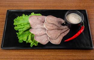 Appetizer with slices of beef on a black plate on a white background photo