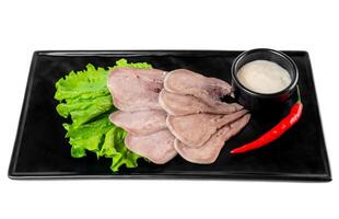Appetizer with slices of tender beef on a black plate on a white background top view photo