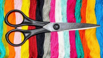 Black scissors on multi-colored skeins of floss. Choosing a color for needlework photo