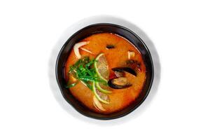 Soup tom yum with seashells and mussels side view on white photo