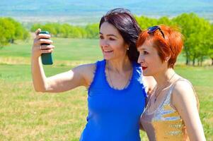 Two Russian sisters holding phone for talking with friends on a call. They sincerely laughing with teeth photo