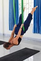 Young hanging woman making aerial or fly yoga pose photo