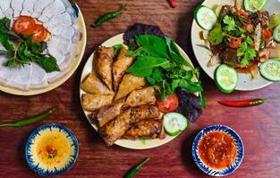 Traditional fried vietnamese spring rolls with pork, rice paper with sauces, meat slices and beef stew photo