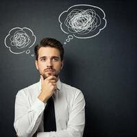 Young man thinking about something in his mind with thought bubbles above his head photo