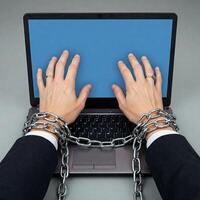 Hands chained to laptop computer photo