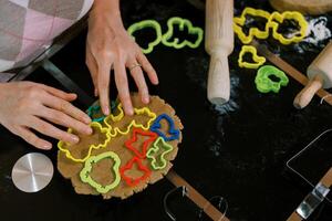 Confectioner distributes multi-colored cookie cutters over the dough on the table. Cropped photo