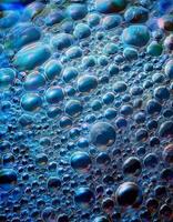 Natural Bubbles Forming in a Vibrant Blue Liquid Under Sunlight Create an Artistic Display of Shapes and Colors photo