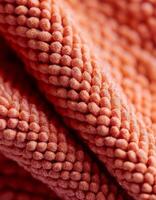 Textured Coral Fabric Close-Up Showcases Intricate Weave and Soft Touch, Ideal for Interior Design and Textile Applications photo