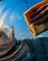 Hand Cleaning Car Windshield on a Sunny Day While Reflections Create Beautiful Patterns photo