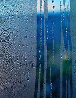 Moist Droplets Sliding Down a Glass Window in a Morning Light Creating a Serene View of Nature Outside photo