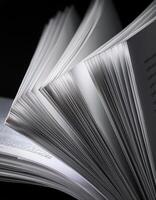 Detailed View of an Open Book With Pages Flipping Amidst a Black Background photo