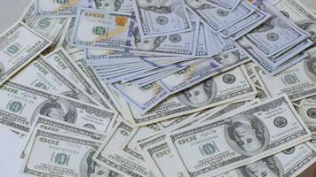 Close-up view of piles of 100 US dollar bills arranged in a scattered manner. Depicts wealth, finance, savings, or economic themes in high detail. video
