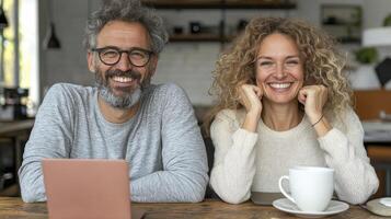 Happy Couple Smiling at Camera with Laptop and Coffee Cup on Wooden Table, a Modern and Cozy Home Interior Scene, Featuring a Man and Woman with Natural Expressions, Showcasing Love and Connection photo