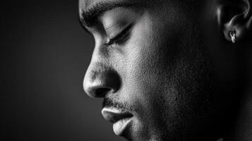 black and white portrait captures man in profile, highlighting his contemplative expression and textured skin. lighting emphasizes details of his face and earring photo