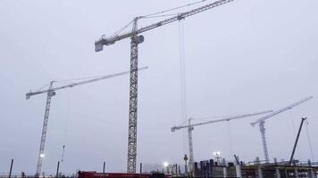 Three cranes are standing in a construction site video