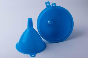 Two blue plastic funnels are displayed against plain background, one standing upright and other lying flat, showcasing their simple design and functionality photo