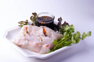 Fresh spring rolls with shrimp and vegetables are served on white plate, accompanied by small bowl of soy sauce and garnished with cilantro and lettuce photo