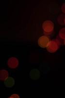 dark abstract image featuring soft, out of focus bokeh lights in red, orange, and green hues, creating warm and festive atmosphere photo