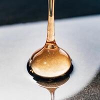 A honey dripping from a spoon on a table photo