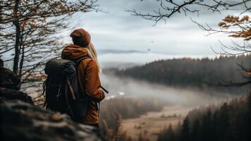 Woman with backpack standing on a mountain overlooking a foggy forest photo