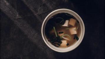 A bowl of soup with tofu and green onions photo