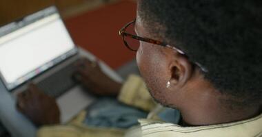 A man wearing glasses is using a laptop computer photo
