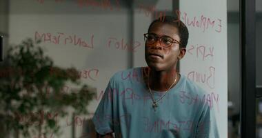 A man with glasses and a blue shirt is looking at a wall with writing on it photo