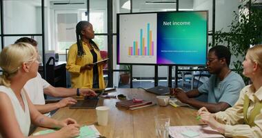 A group of people sitting around a table with a woman giving a presentation photo