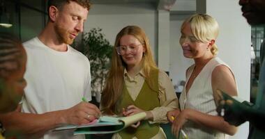 A group of people standing around a table with a notebook photo