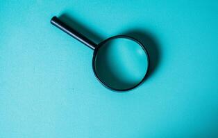 Magnifying Glass on Teal Background for Investigation Concept. CloseUp of Magnifying Glass for Search and Discovery Theme photo