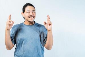 Hopeful man making a wish with fingers isolated. Optimistic guy smiling and making a wish isolated photo