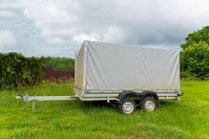 A two-axle semi-trailer is parked on a lawn. photo