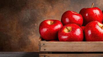 Fresh red apples in a rustic wooden crate on a textured background. photo