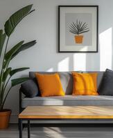 A grey couch with orange pillows and a plant photo
