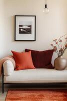 A white couch with orange pillows and a vase photo