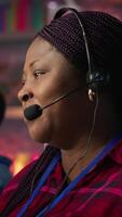 Vertical Smiling call center employee handling customer concerns, doing complaint resolution. Persuasive customer service agent contacts clients to inform them about new products, doing upselling camera A video