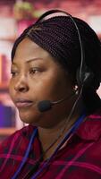 Vertical Happy call center agent providing step by step guidance to customers. Smiling customer center worker at PC desk walking clients through technical solutions during call, camera A video
