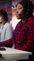 Vertical Customer center employee gesturing loud colleague to quiet down during conversation with client. Call center worker upset by noises in office while talking to customers using headphones mic, camera B video