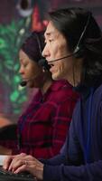 Vertical Experienced call center employee listening to customer inquiries and complaints. Asian senior customer service representative assisting customers with issues related to products or services, camera A video