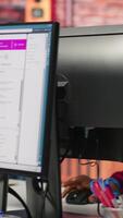 Vertical Call center worker tracking shipments at work, looking at computer screen, handling delivery delays. Customer center agent uses software to locate clients packages and provide status updates, camera A video