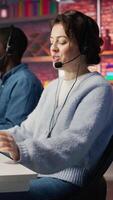 Vertical Happy call center employee working on PC, doing account management in office. Cheerful customer support agent handling inbound calls, assisting customers with inquiries, camera B close up video