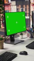 Vertical Green screen mockup computer in office next to displays showing data analytics dashboards. Chroma key isolated screen PC in company workspace next to monitor displaying metrics and data video