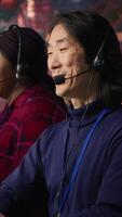 Vertical Multiethnic team of call center agents answering clients technical inquiries about hardware issue. Multiracial customer support workers in office doing job using PC to troubleshoot problems, camera A video