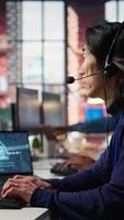 Vertical Customer center employee uses artificial intelligence LLM assistant to locate clients packages. Call center agents track shipments in office, using AI chatbot to generate solutions, camera B video