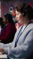 Vertical Call center agent uses artificial intelligence to enhance customer interactions and resolve inquiries efficiently. Woman in customer service office using AI communication technologies, camera B video