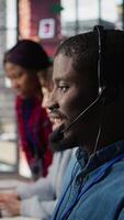Vertical Diverse customer center workers assisting clients with installing software. Multiethnic team of call center agents using remote access tools to connect to customer devices, fixing errors, camera B video