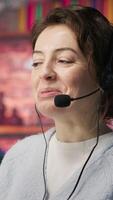 Vertical Friendly call center employee talking in audio headset, assisting customers in office. Happy customer support operator communicating with clients during telephone call, camera A close up video
